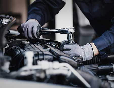 Mechanic using a ratchet to service a gas or diesel engine