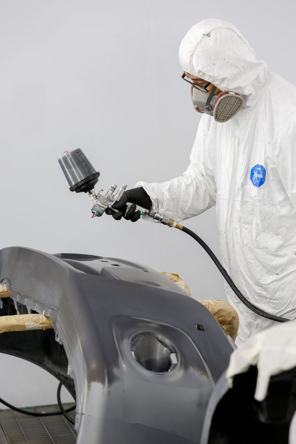 Body shop technician spray painting a panel
